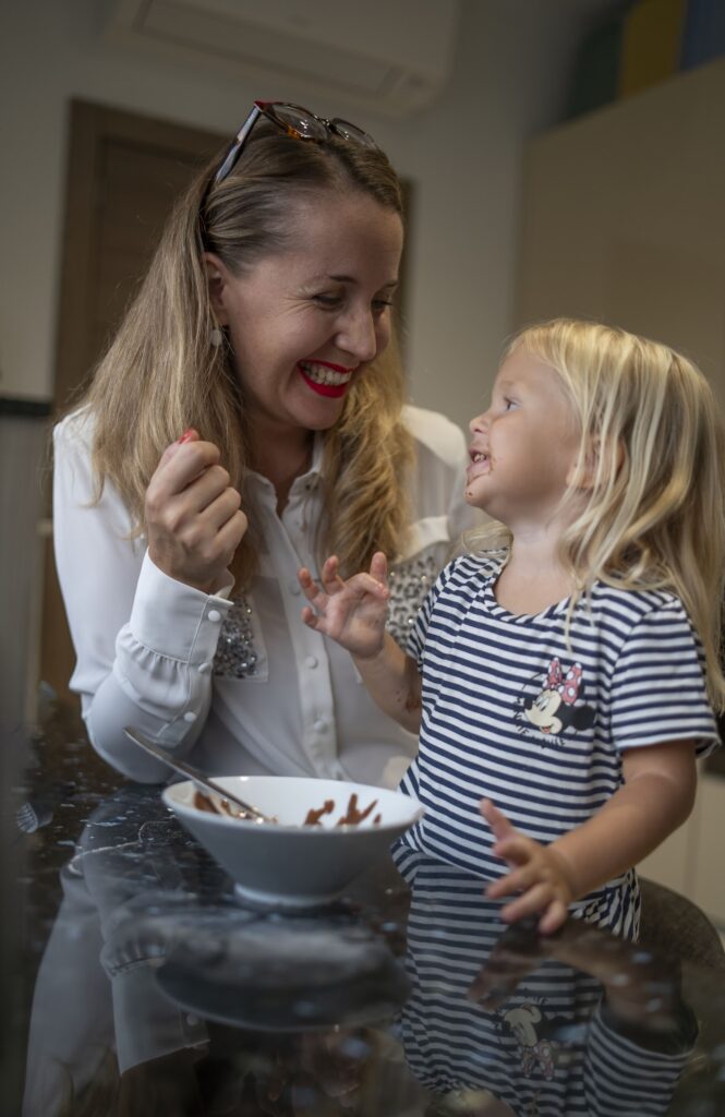 Jana Alles lacht mit ihrer kleinen Tochter in der Küche, beide mit Schokolade an den Händen